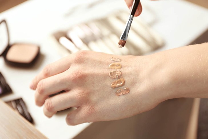 Female visagiste applying cosmetics onto hand