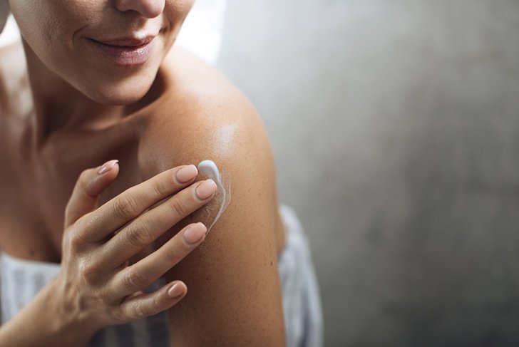 woman putting lotion on arm