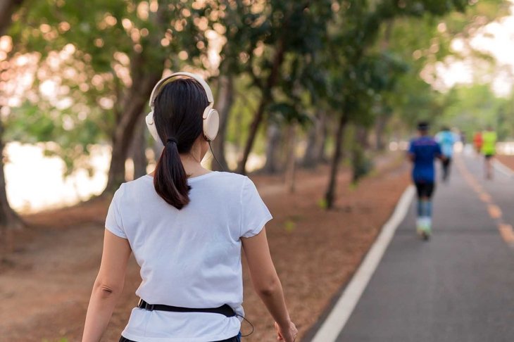 Woman exercise walking in the park listening to music with headphone