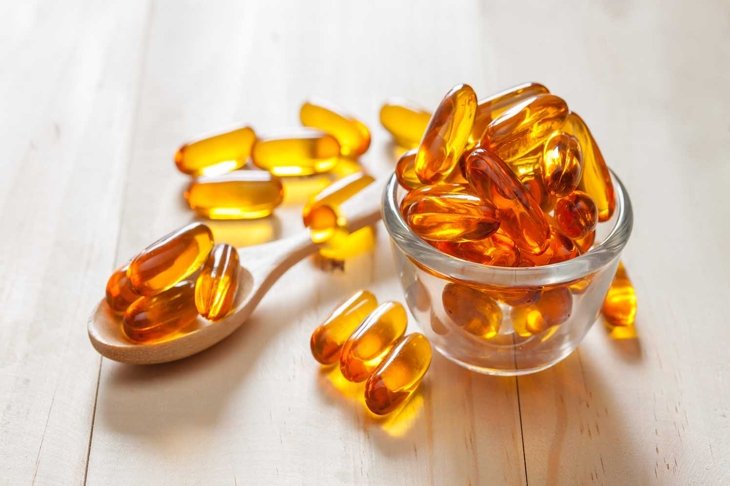 Fish oil capsules on wooden background and texture, vitamin D supplement, selective focus